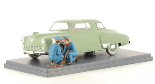Studebaker verte avec deux personnages en train de changer une roue dans Tintin.