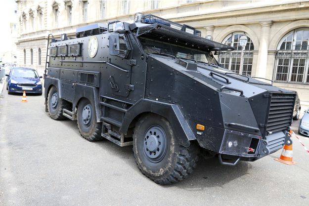 Nexter Titus noir à l'arrêt avec 6 roues devant bâtiment ministère de l'intérieur.