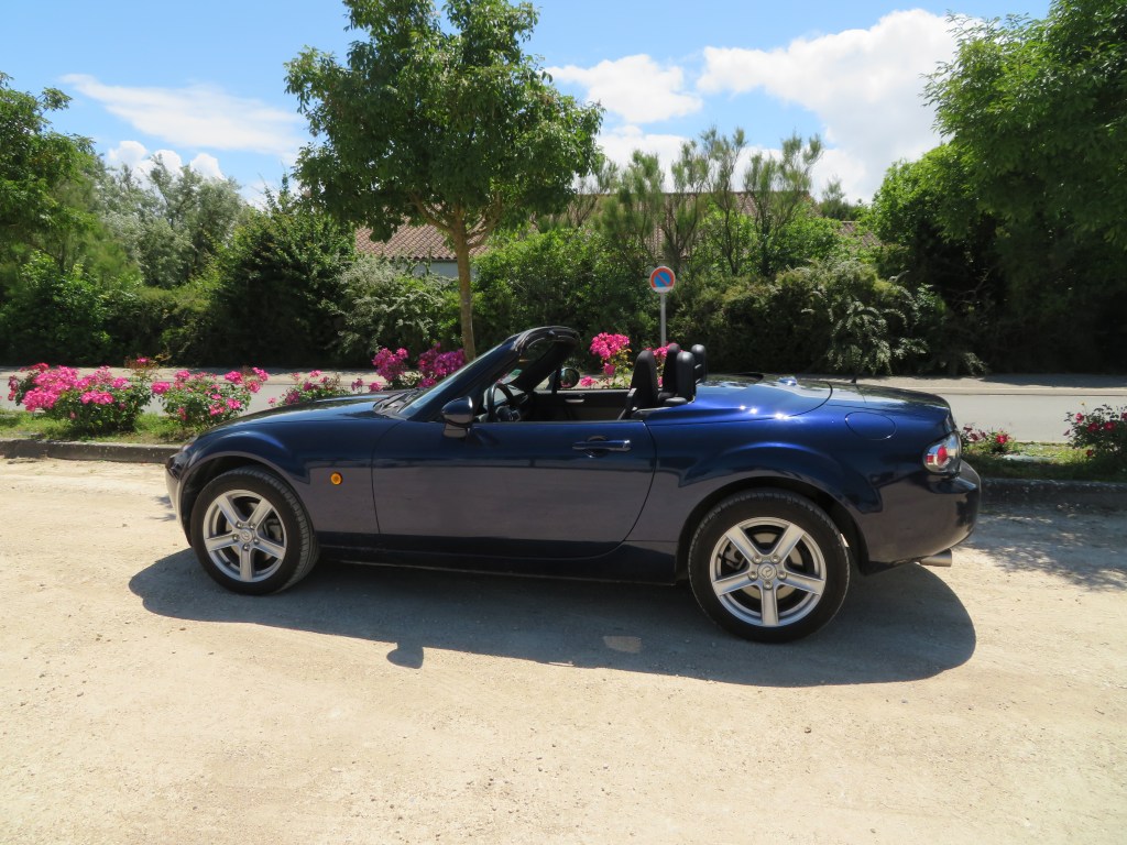 Mazda MX-5 NC bleue en mode cabriolet.