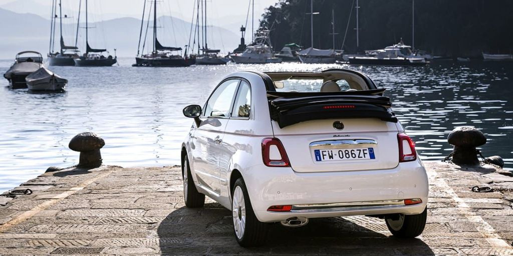 Fiat 500 cabriolet blanche décapotée garée le long de l'eau.