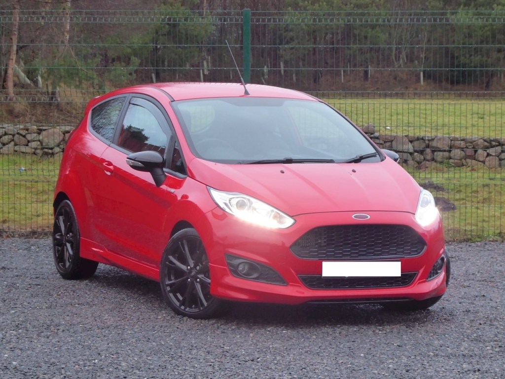 Ford Fiesta 5 ST rouge en photo devant grillage.