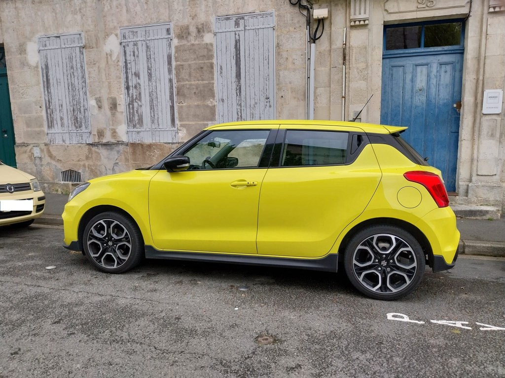 Suzuki Swift Sport 4 jaune vue de profil dans rue.