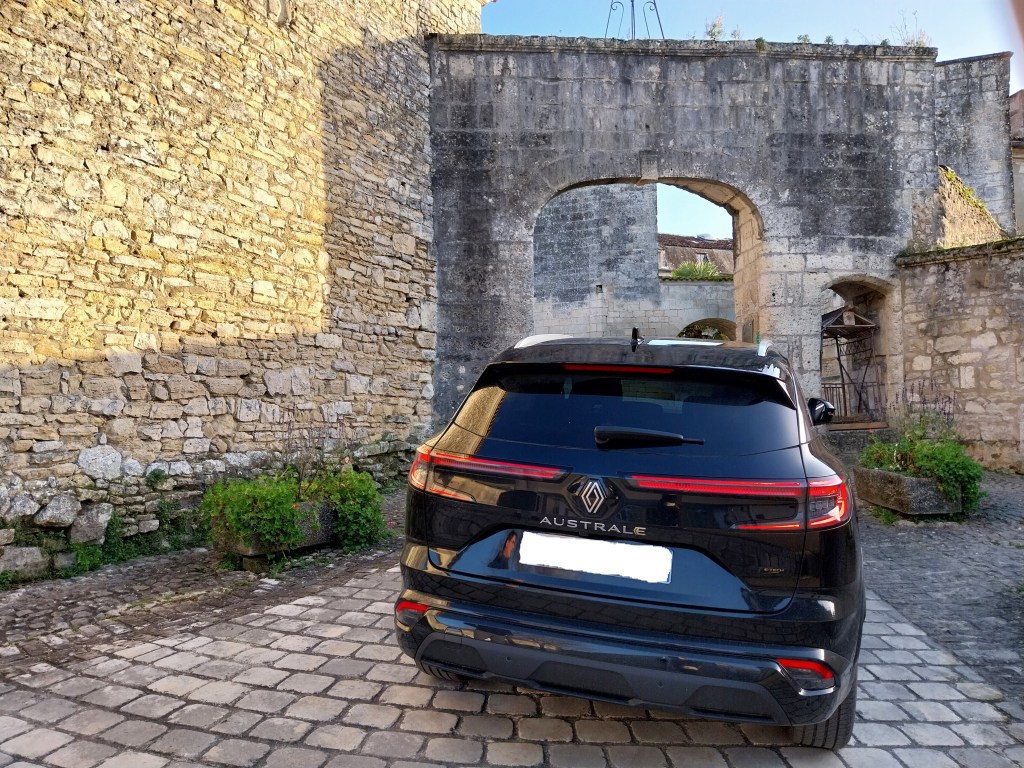Renault Austral hybride noir pris en photo à l'arrière devant belle abbaye.
