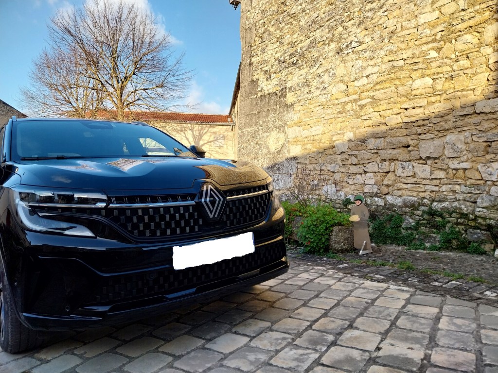 Renault Austral full-hybrid noir pris en photo de l'avant devant belle abbaye.